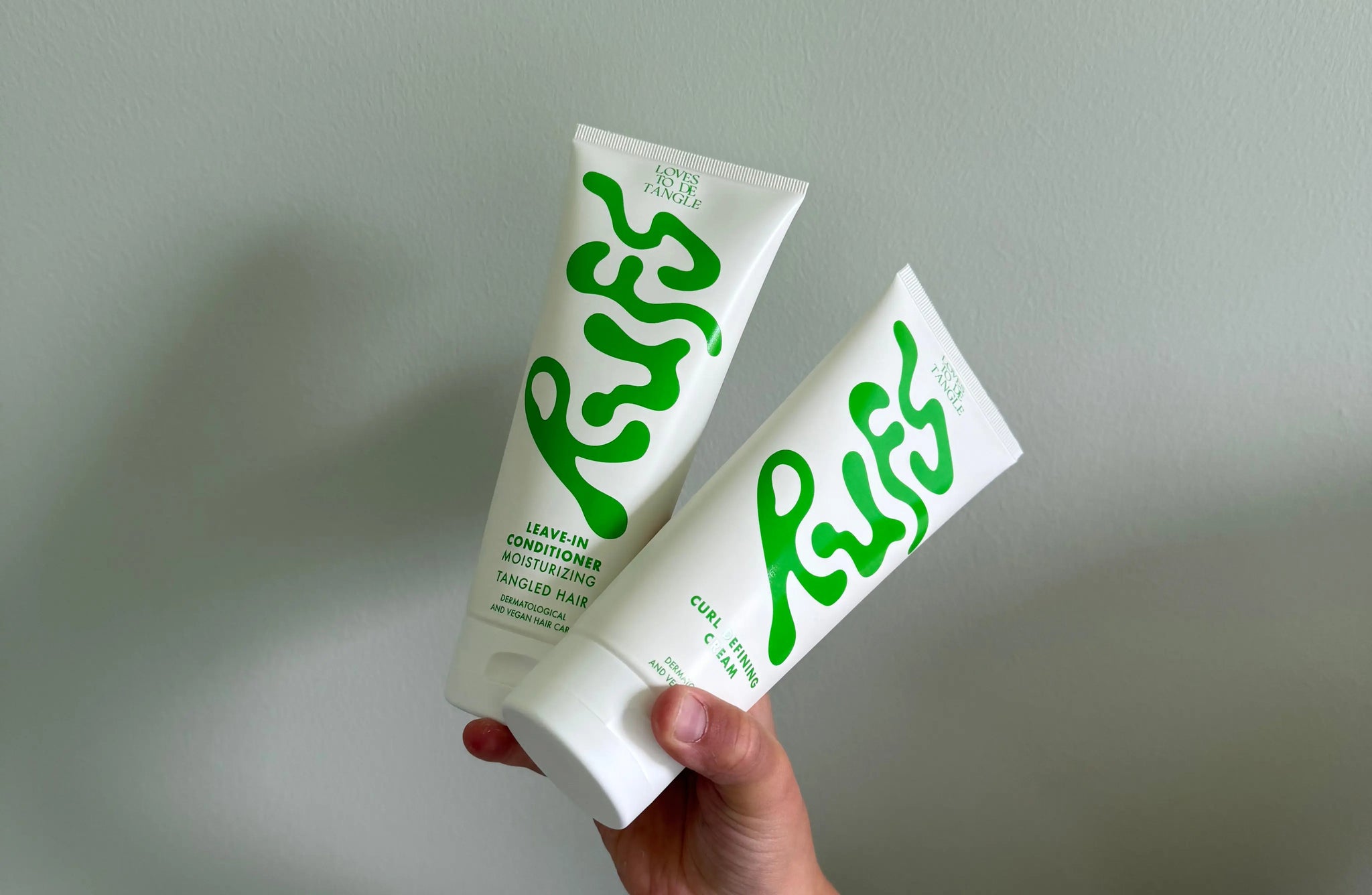 A girl holding one curl defining cream and one leave in conditioner